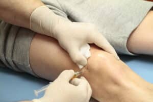 Doctor administers PRP in a patient's knee using a fine needle