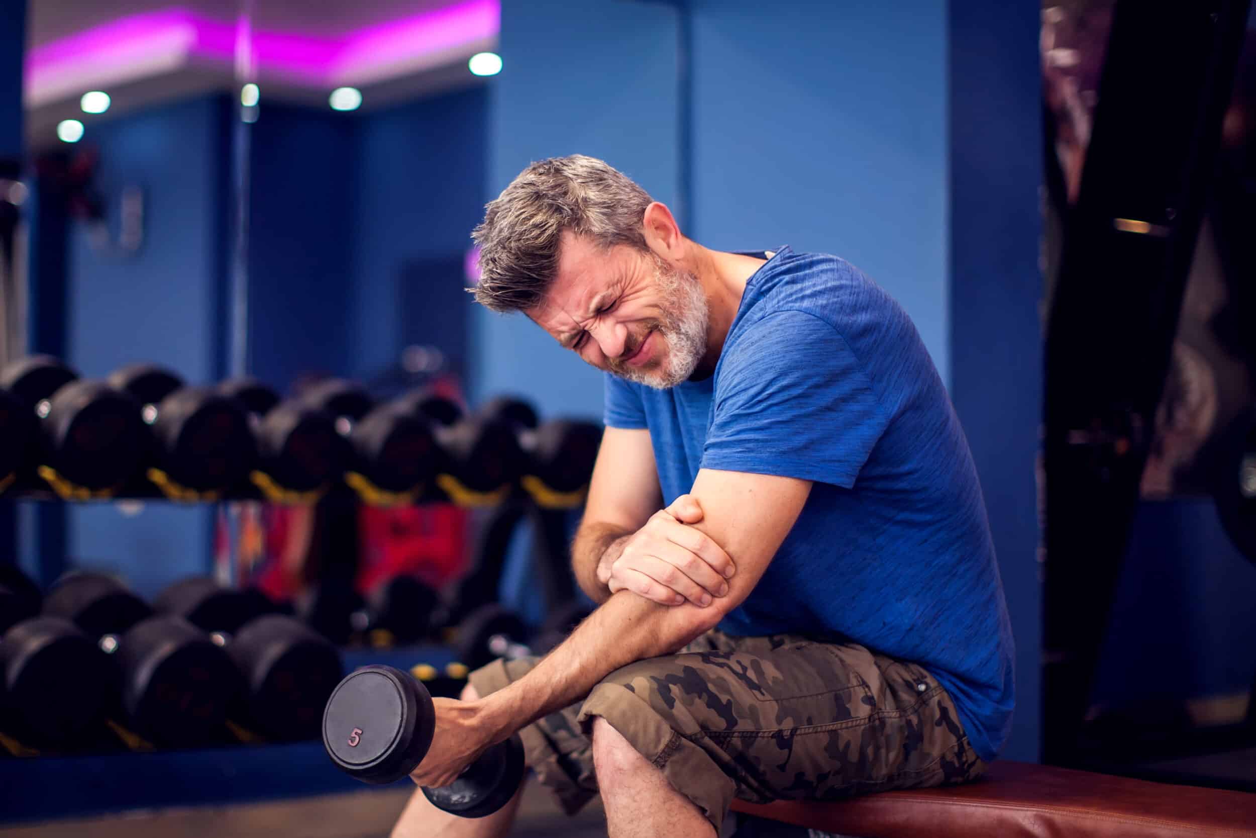 Man clutches his left elbow, wincing in pain