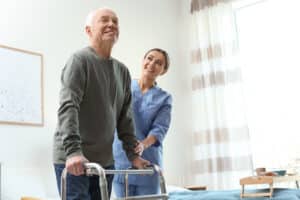 Smiling man uses a walker after hip replacement surgery