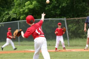 Youth baseball player throwing a ball during practice, highlighting repetitive arm motion associated with Little League elbow.