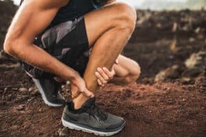 Man holding his ankle after an Achilles tendon strain in Wichita